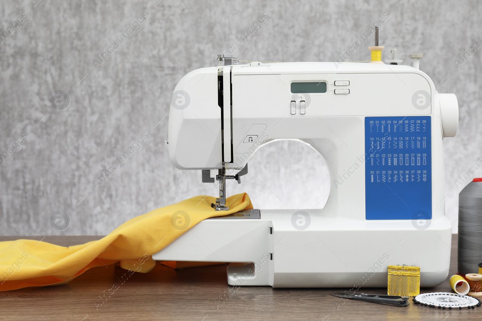 Photo of Sewing machine with fabric and craft accessories on wooden table