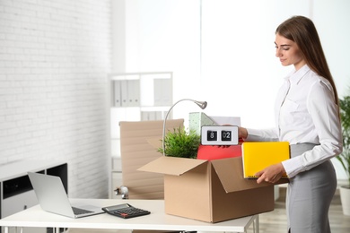 Photo of Happy young woman packing stuff in box at office