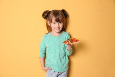 Cute little girl with slice of pizza on color background