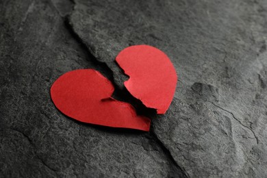 Photo of Halves of torn red paper heart on dark grey table, closeup. Broken heart
