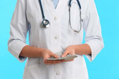 Doctor with bribe on light blue background, closeup. Corruption in medicine