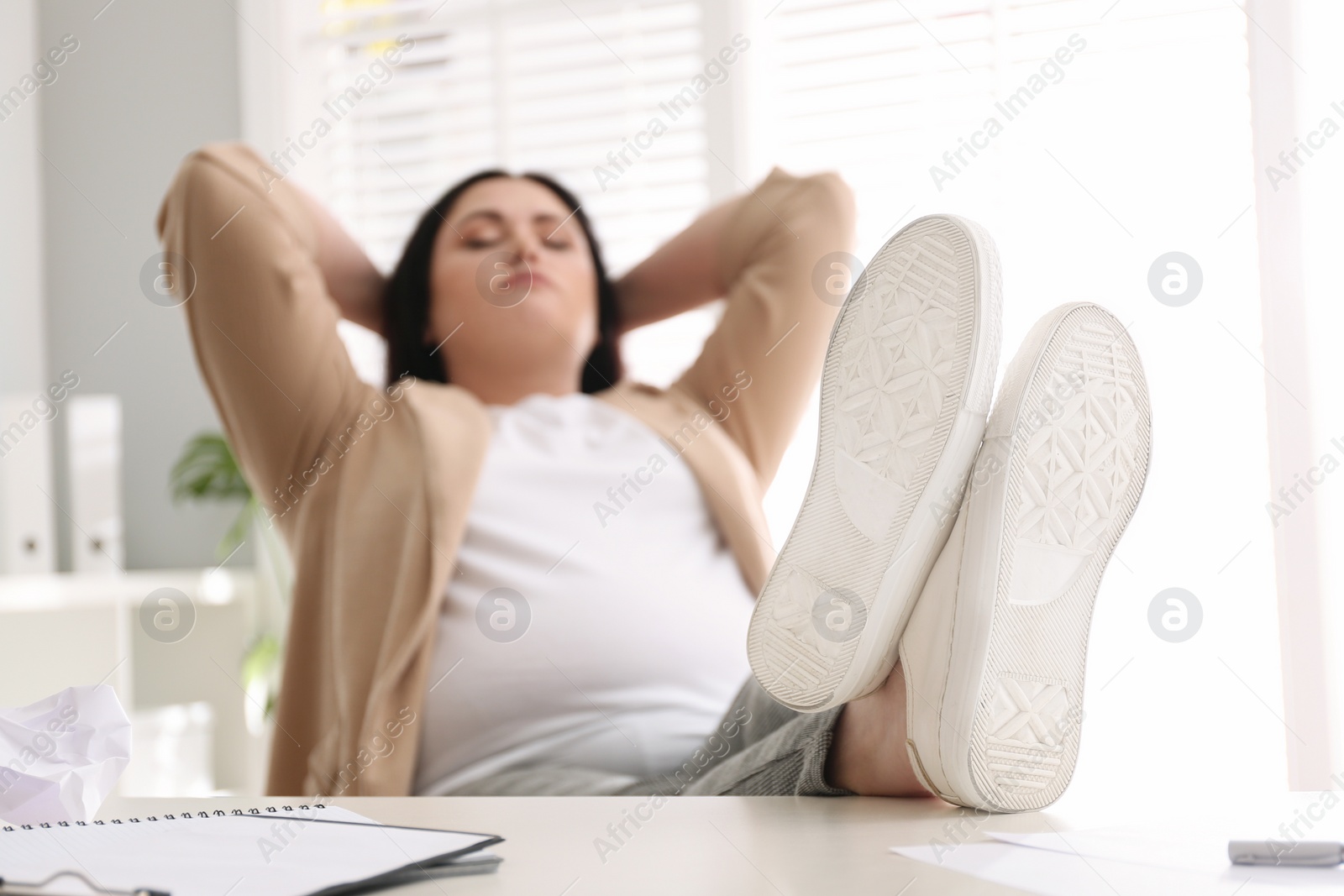 Photo of Lazy overweight worker with feet on desk in office