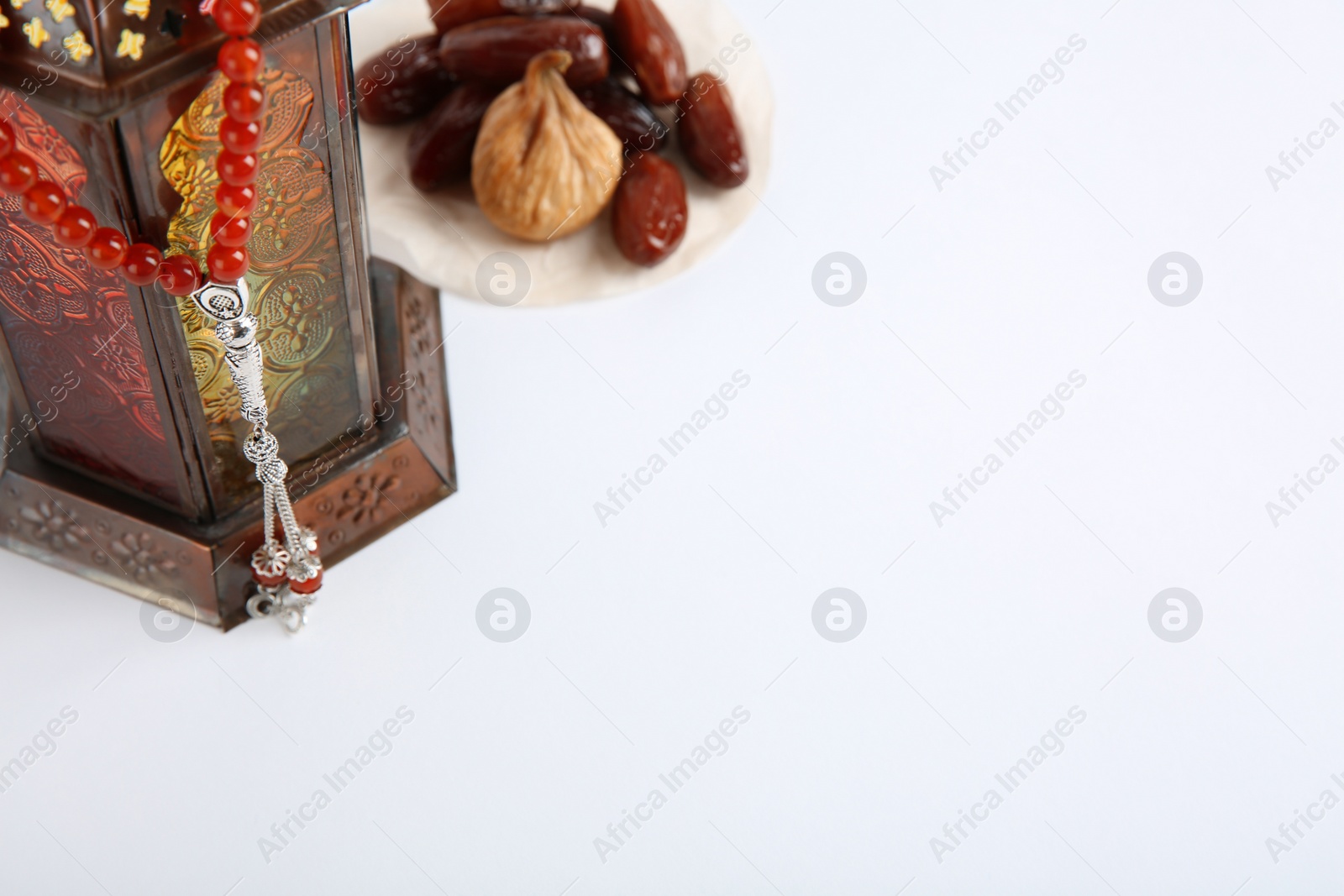 Photo of Muslim lamp, dates and prayer beads on white background. Space for text