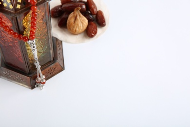 Photo of Muslim lamp, dates and prayer beads on white background. Space for text