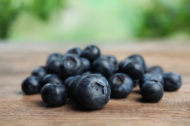 Pile of tasty fresh blueberries on wooden table, closeup