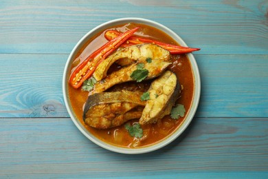 Tasty fish curry on light blue wooden table, top view. Indian cuisine