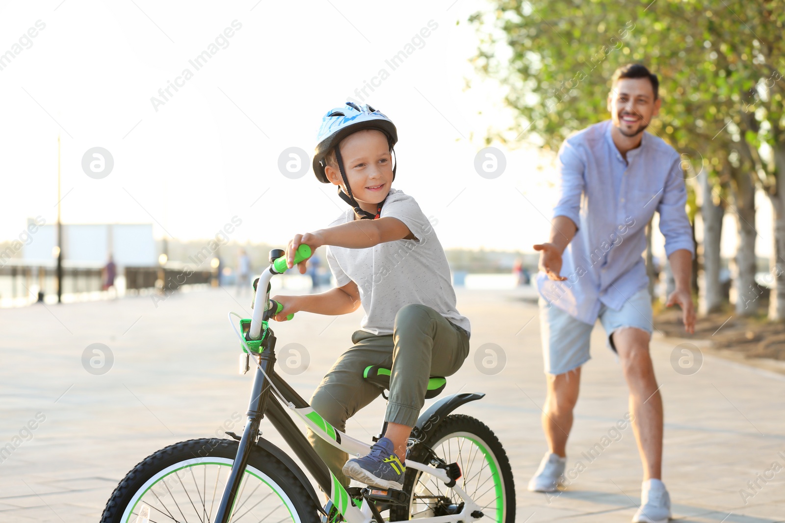 Photo of Father teaching son to ride bicycle on street