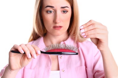 Emotional woman holding brush with fallen hair on white background