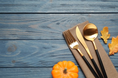 Photo of Cutlery, autumn leaves and pumpkin on blue wooden table, flat lay with space for text. Thanksgiving Day
