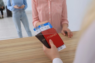 Agent giving passports with tickets to client at check-in desk in airport, closeup