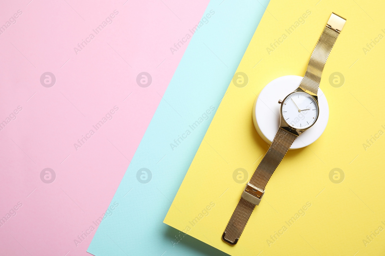 Photo of Stylish golden wristwatch on color background, top view. Space for text