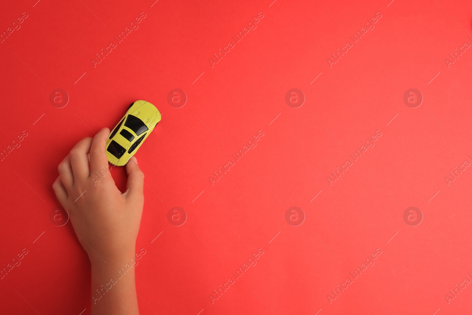 Photo of Child playing with toy car on red background, top view. Space for text