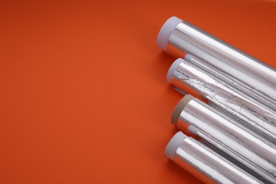 Photo of Rolls of aluminum foil on red background, closeup. Space for text