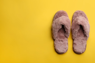 Pair of stylish soft slippers on yellow background, flat lay. Space for text