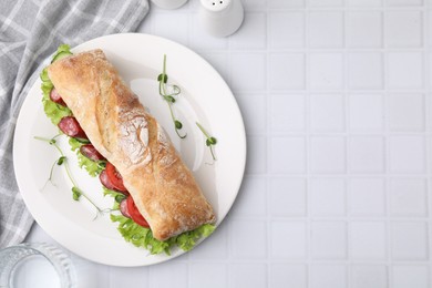 Delicious sandwich with sausages and vegetables on white tiled table, top view. Space for text