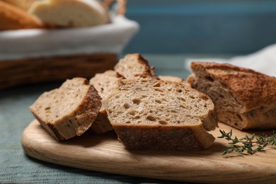 Photo of Cut buckwheat baguette with thyme on light blue wooden table, closeup