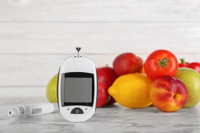 Photo of Digital glucometer, fruits and vegetables on table. Diabetes concept