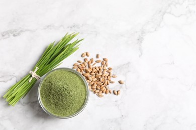 Wheat grass powder in bowl, seeds and fresh sprouts on white marble table, flat lay. Space for text