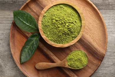 Photo of Green matcha powder and leaves on wooden table, top view