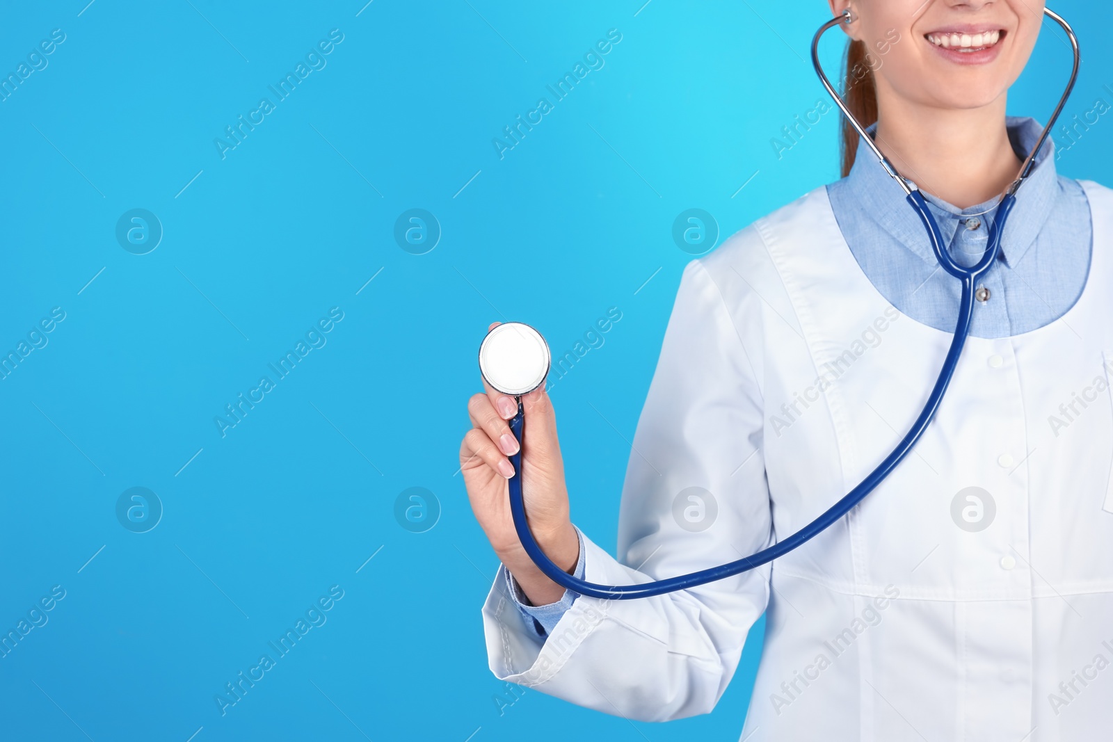 Photo of Female doctor holding stethoscope on color background, closeup with space for text