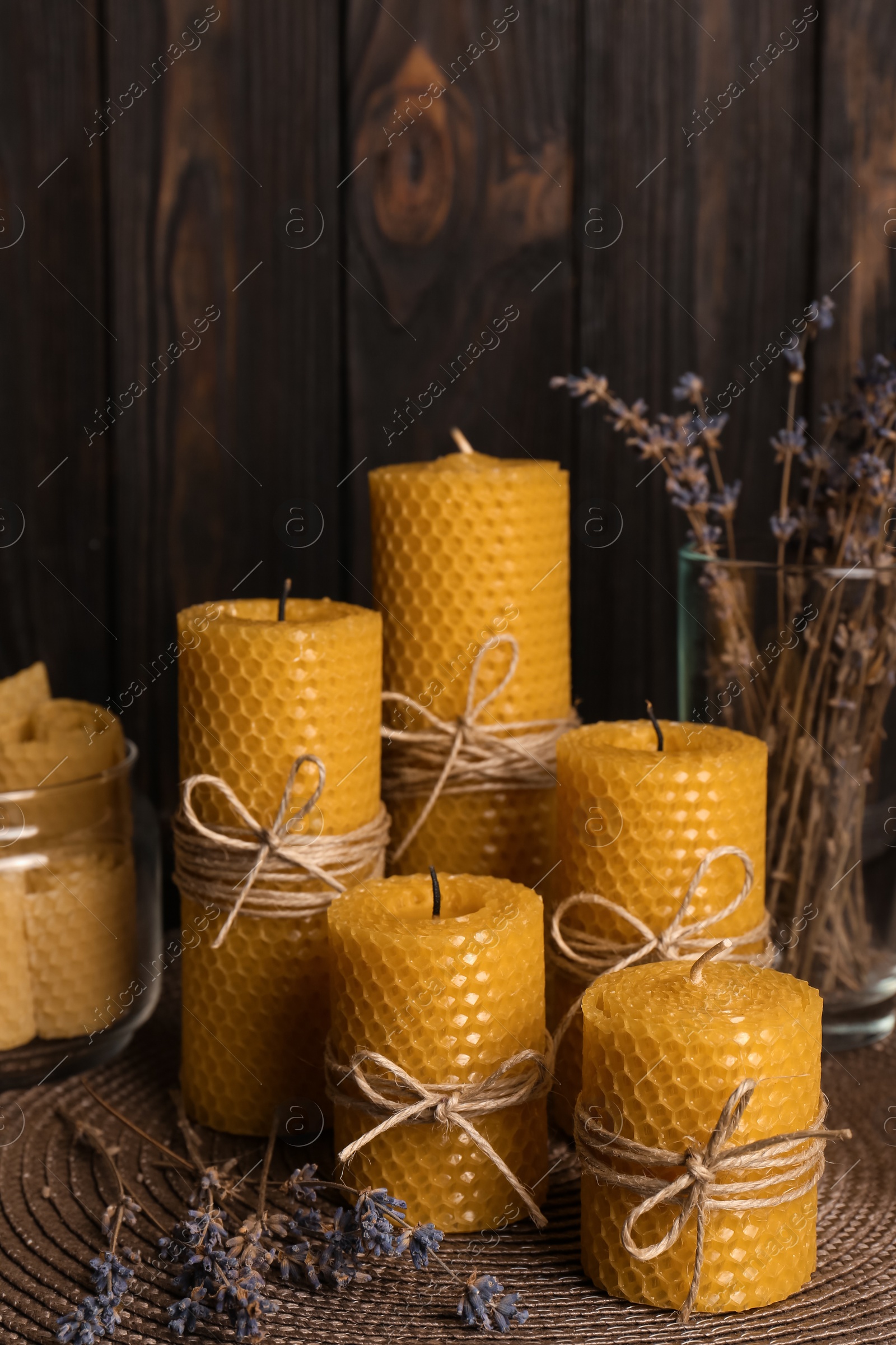 Photo of Beautiful beeswax candles and dried lavender flowers on table