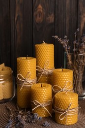 Beautiful beeswax candles and dried lavender flowers on table