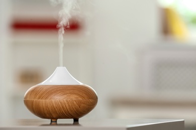 Aroma oil diffuser lamp on table against blurred background