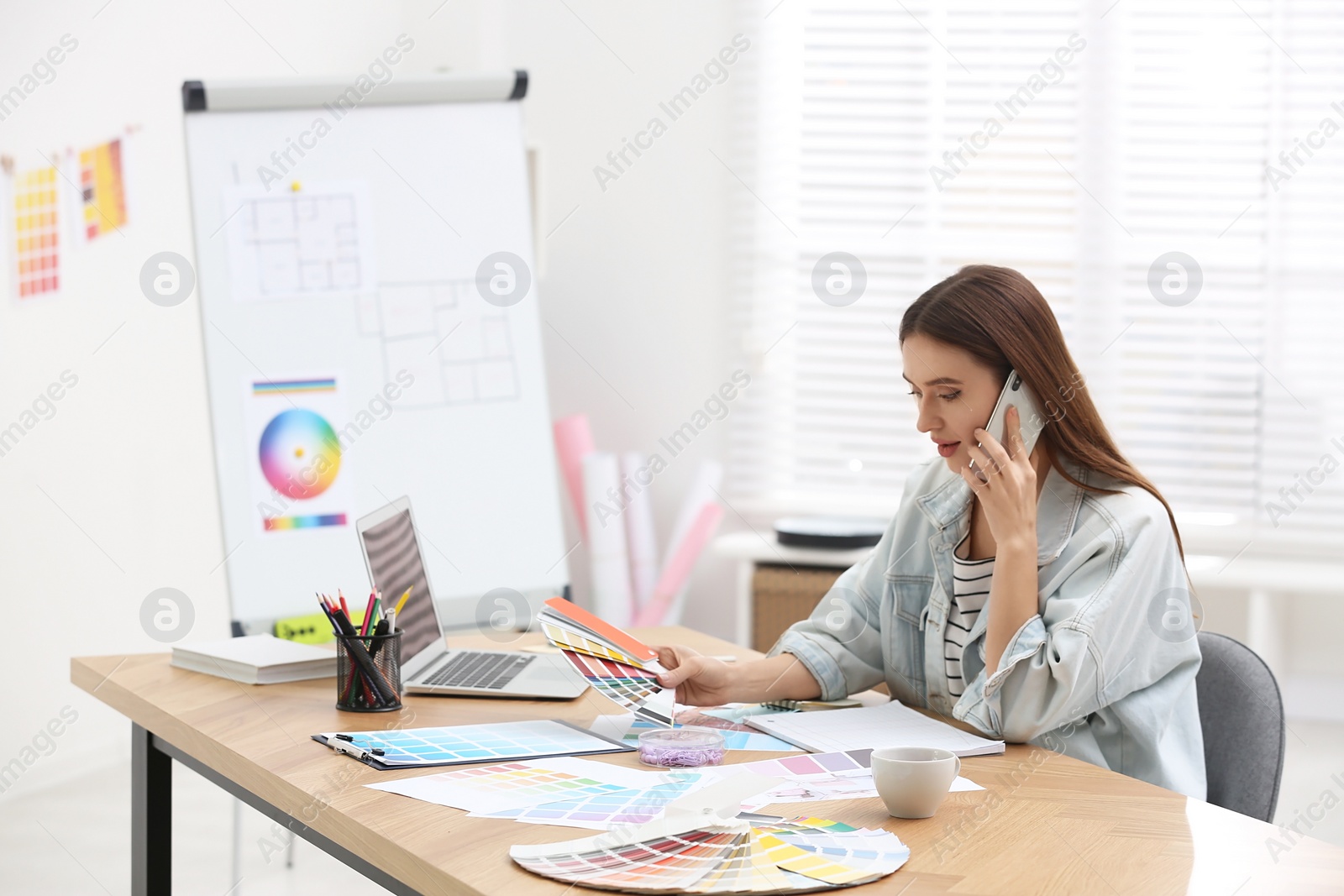 Photo of Interior designer talking on mobile phone in office