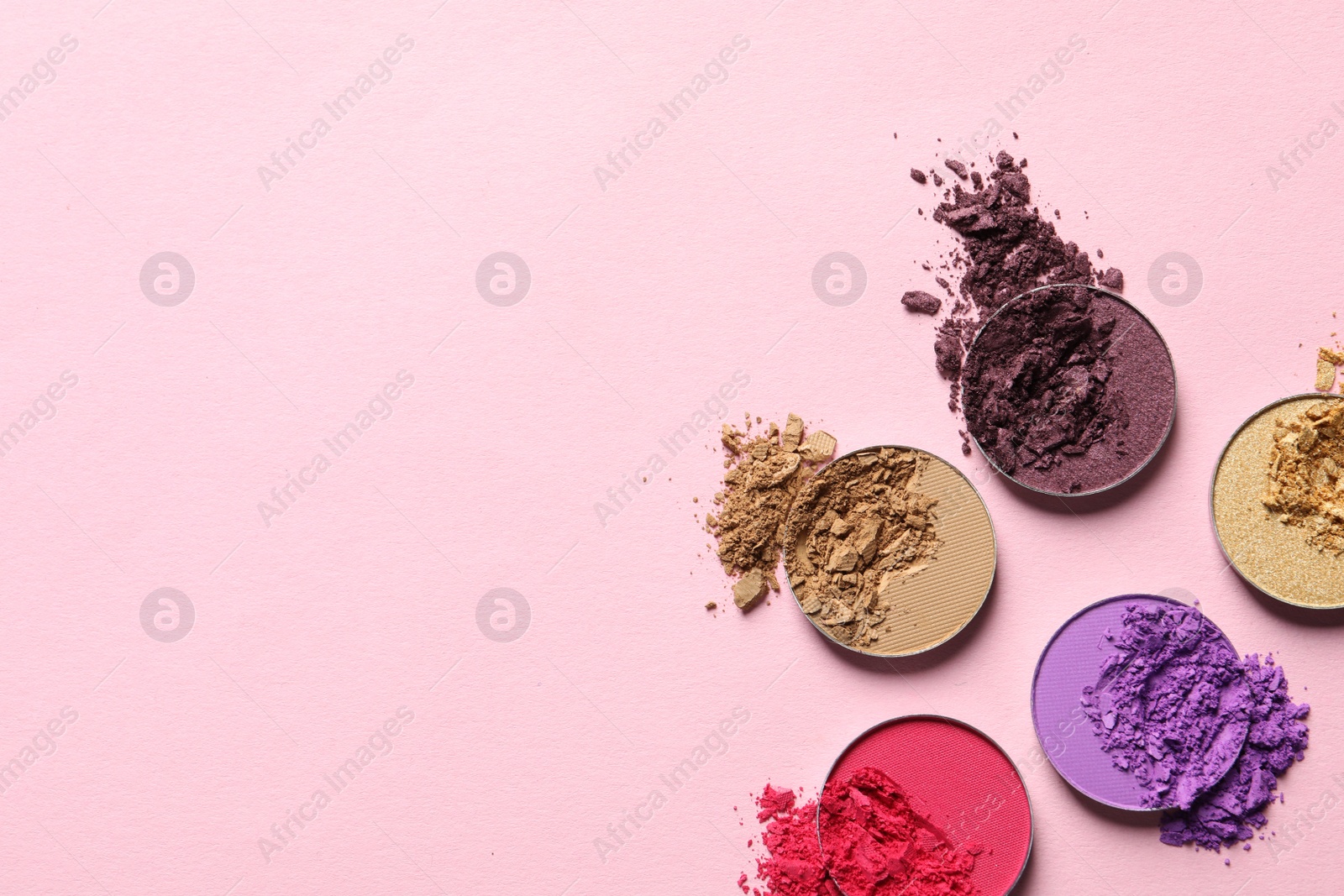 Photo of Different crushed eye shadows on pink background, flat lay. Space for text