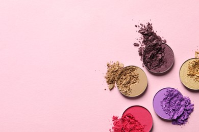 Different crushed eye shadows on pink background, flat lay. Space for text