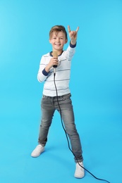 Cute boy with microphone on color background