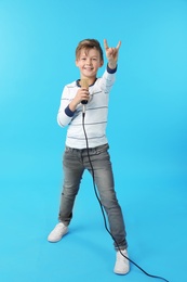 Photo of Cute boy with microphone on color background