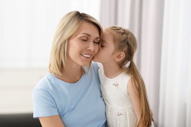 Photo of Daughter kissing her happy mother at home