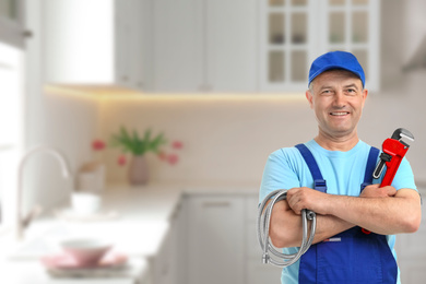 Plumber with pipe wrench and hose in kitchen, space for text