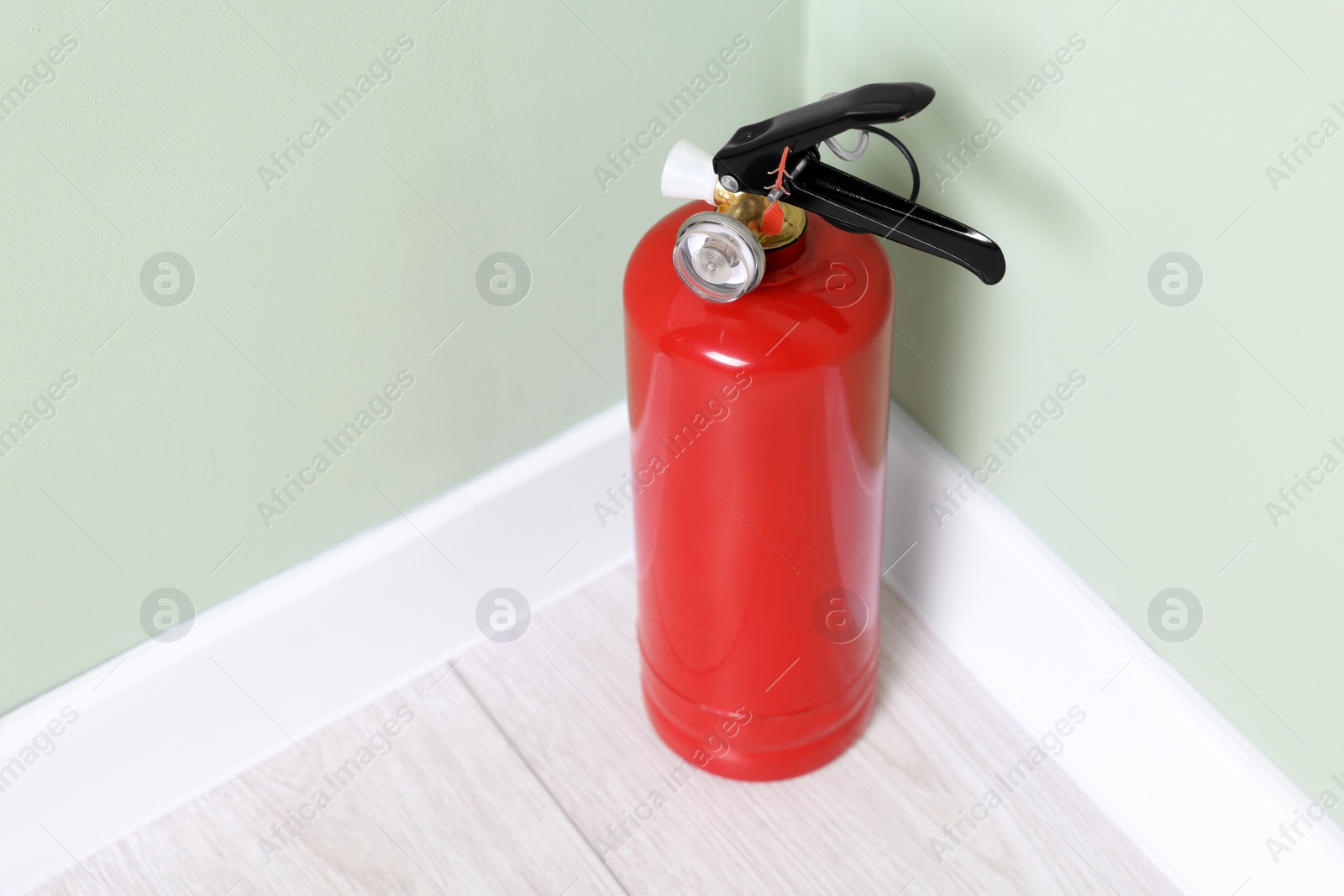 Photo of Red fire extinguisher near light green wall