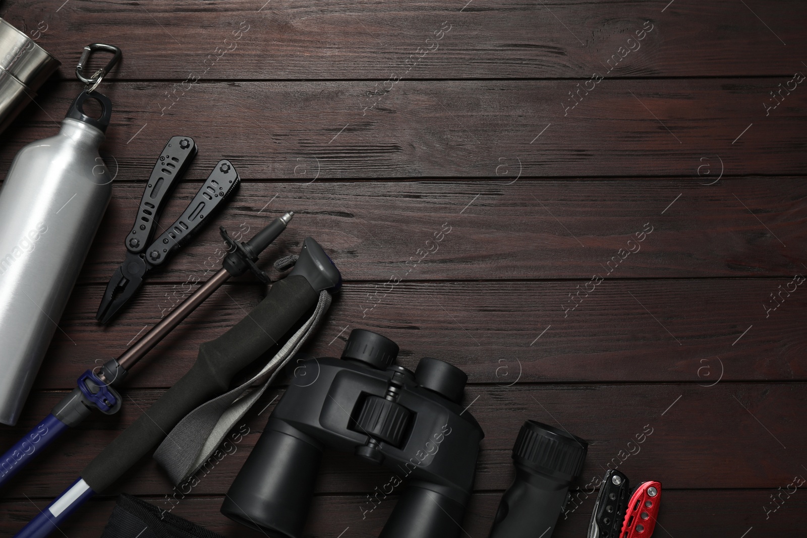 Photo of Flat lay composition with trekking poles and other hiking equipment on wooden background, space for text