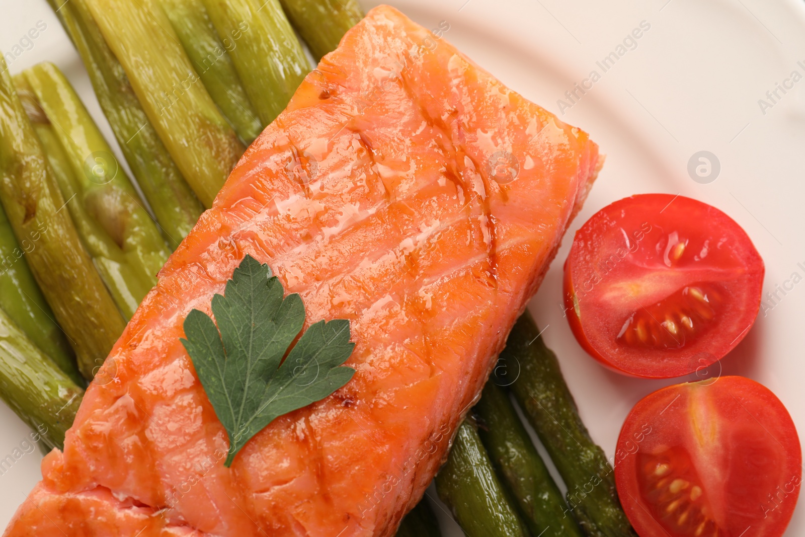 Photo of Plate with tasty grilled salmon, tomatoes and asparagus, top view