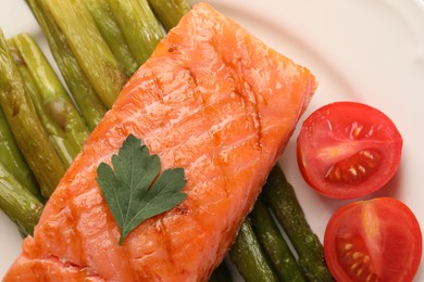 Photo of Plate with tasty grilled salmon, tomatoes and asparagus, top view