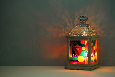 Photo of Decorative Arabic lantern on table against dark background. Space for text