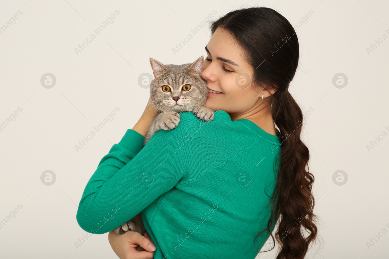 Photo of Young woman with adorable cat on light background