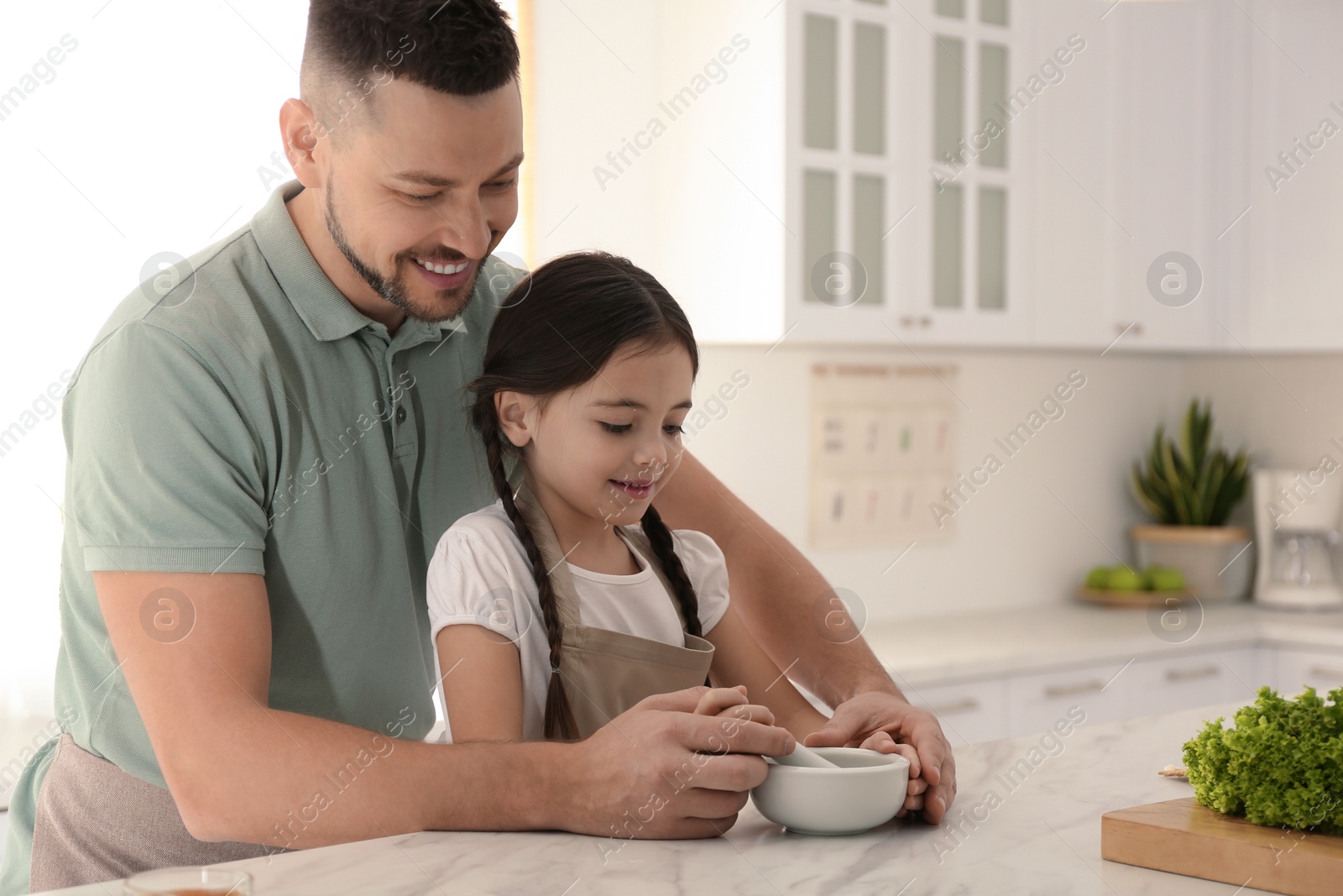 Photo of Father and daughter with mortar in kitchen. Cooking together
