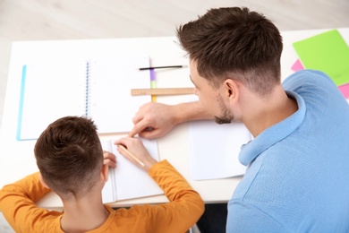 Photo of Dad helping his son with homework in room, above view