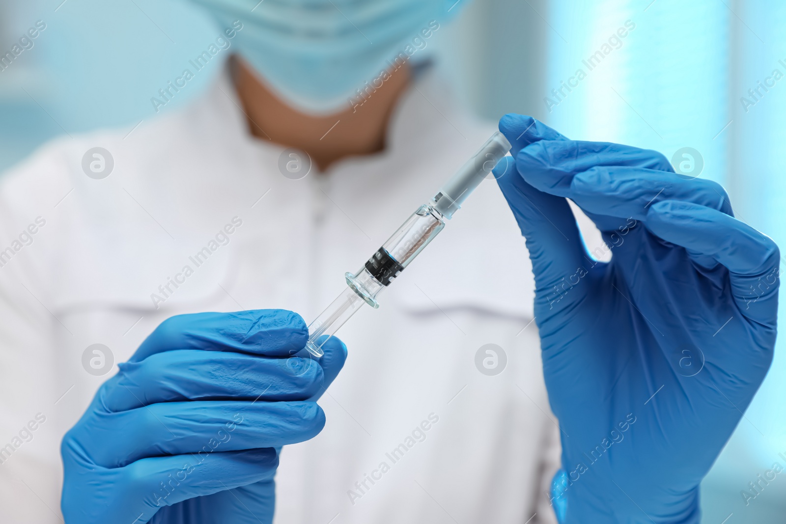 Photo of Doctor holding syringe with COVID-19 vaccine on blurred background, closeup