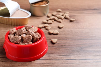 Photo of Wet and dry pet food on wooden table. Space for text