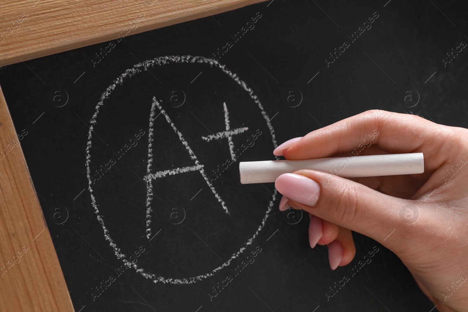 Photo of School grade. Teacher writing letter A and plus symbol with chalk on blackboard, closeup