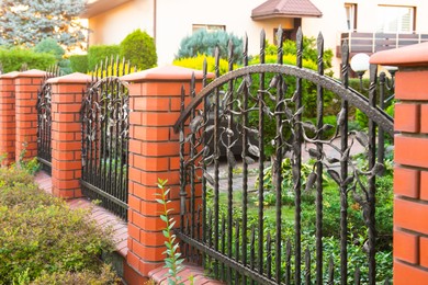 Bushes and beautiful brick fence with iron railing outdoors