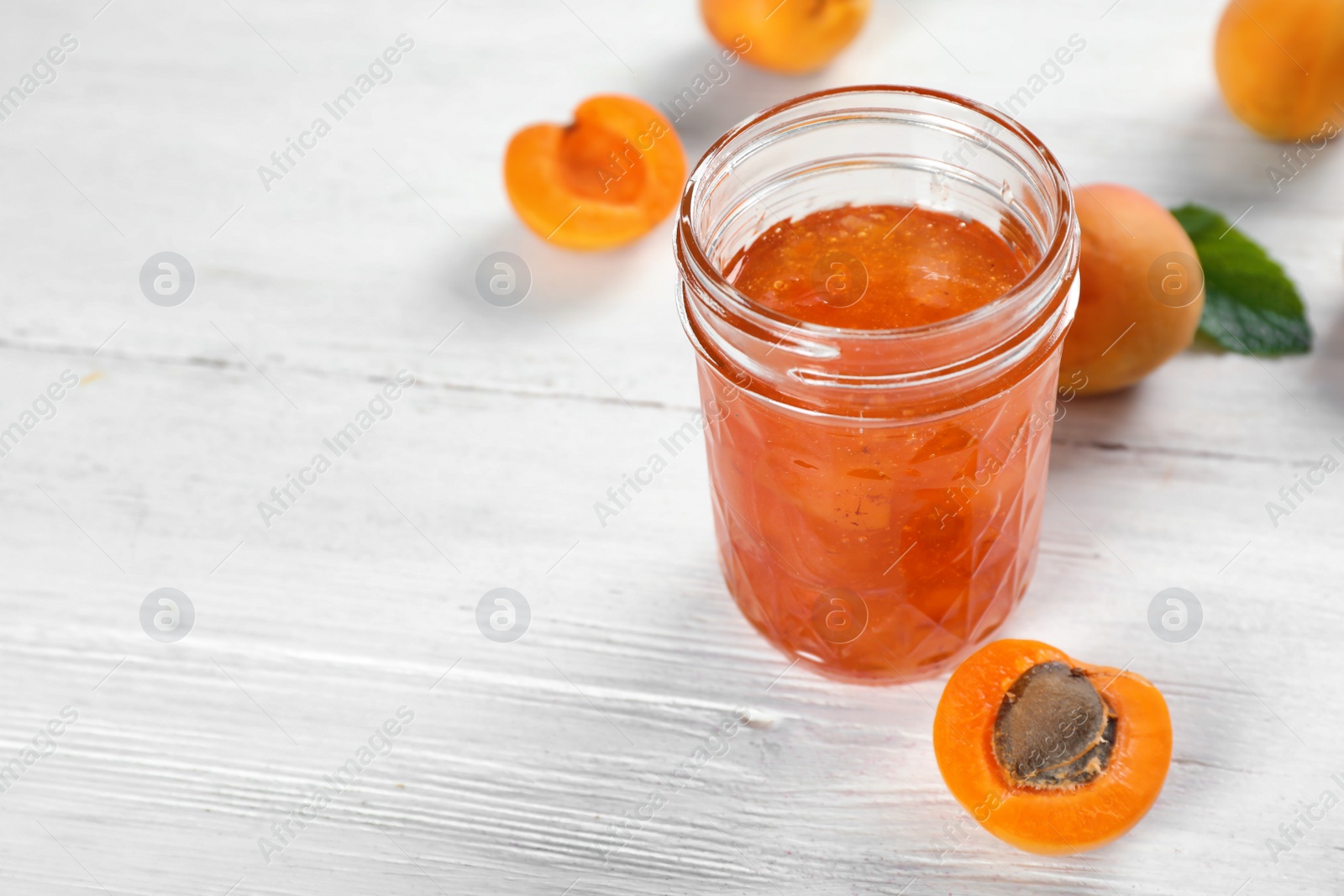 Photo of Jar with tasty apricot jam on table