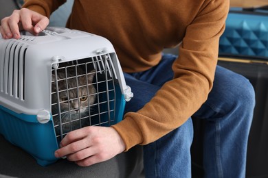 Travel with pet. Man closing carrier with cat on sofa indoors, closeup