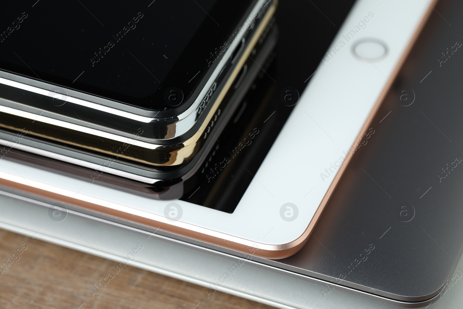 Photo of Stack of electronic devices on wooden table, closeup