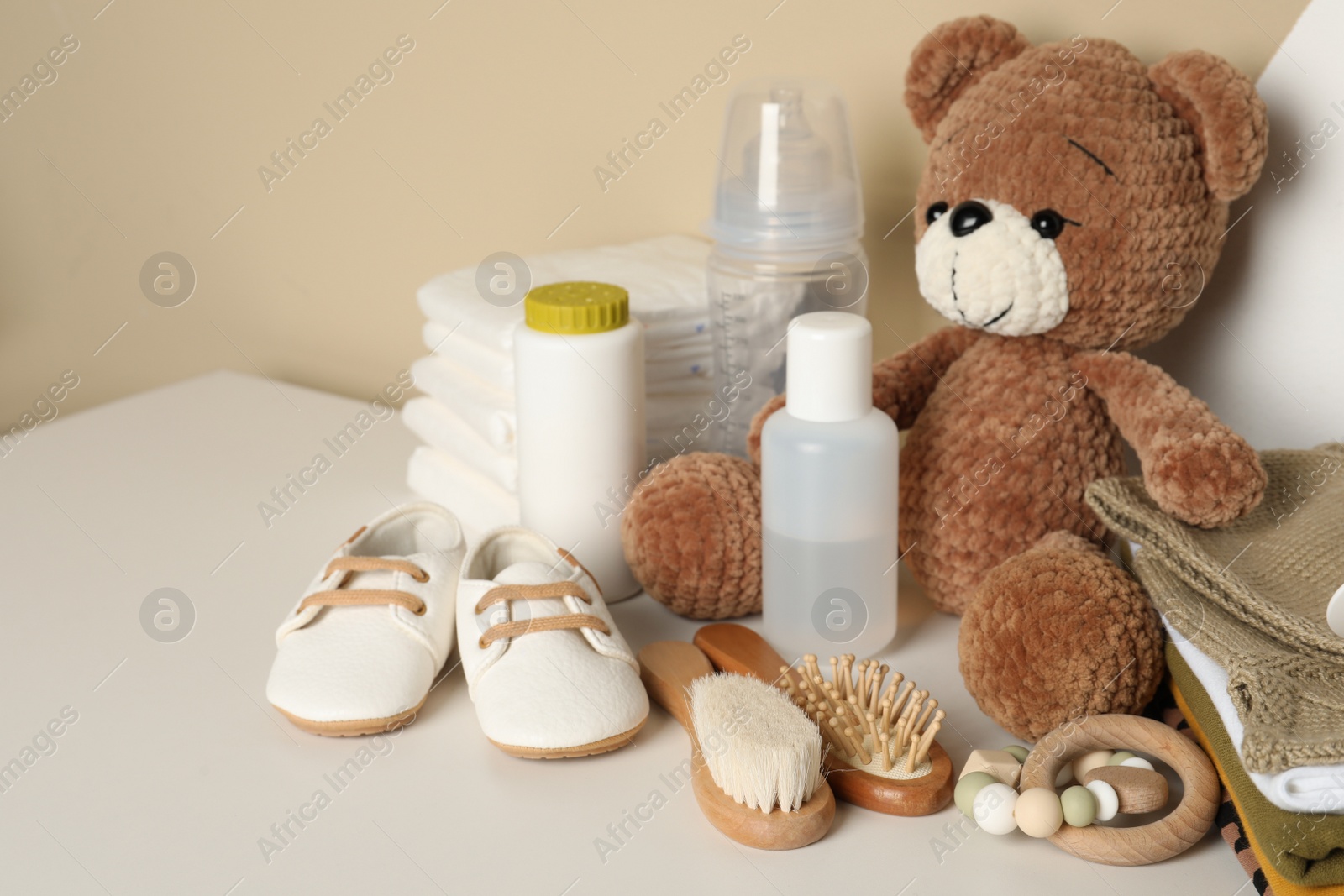 Photo of Baby clothes, toy bear and accessories on white table